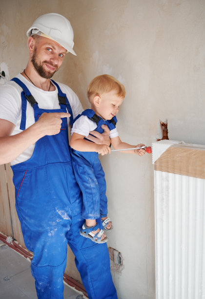 快乐的父亲和小儿子在公寓安装暖气片。图片下载