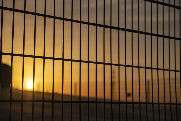 透过铁栅栏看到美丽的日落图片下载