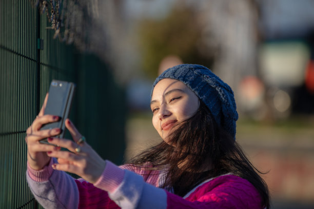 年轻的女孩在日落时分自拍。图片下载