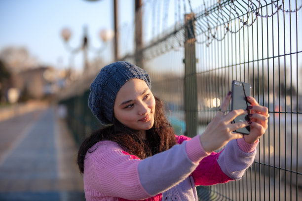 年轻的女孩在日落时分自拍。图片下载