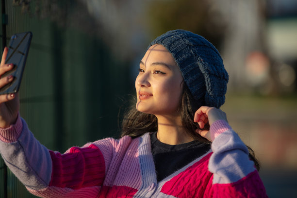 年轻的女孩在日落时分自拍。图片下载