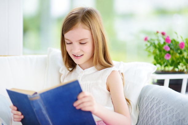 可爱的小女孩在白色的客厅看书图片下载