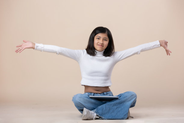 墨西哥女孩坐在地板上快乐的表情与平板电脑图片下载