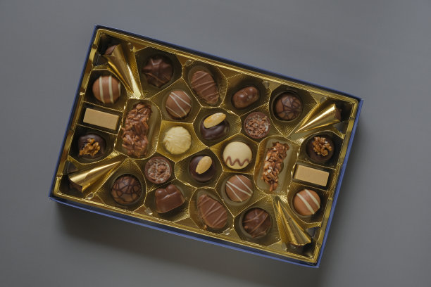 各色巧克力糖果装在灰色背景的盒子里。巧克力盒。牛奶巧克力糖果。糖果和甜点。各式糖果盒图片下载