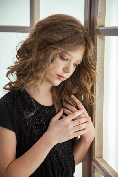 悲伤的少女形象在时尚的黑色连衣裙靠近大窗户室内，悲伤的眼睛。画像沉思可爱的小姐，想着等待。儿童情感概念。复制广告的文字空间图片下载