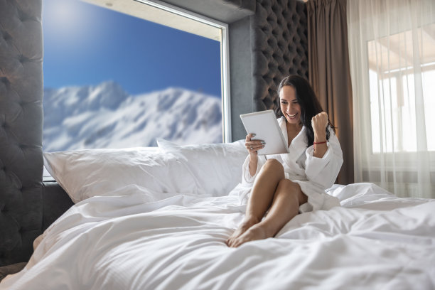 年轻女子在庆祝中了网上彩票或她在酒店房间里做了一笔好买卖，脸上带着愉快的表情。图片下载