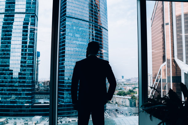 自信的男性经理站在办公室的窗口图片下载