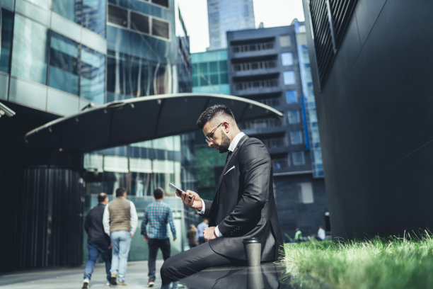 成年自信优雅的经理带着外卖热饮在城市里使用智能手机图片下载