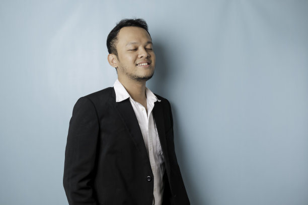 照片中，穿着被蓝色背景隔开的西装的亚洲男性正在微笑图片下载