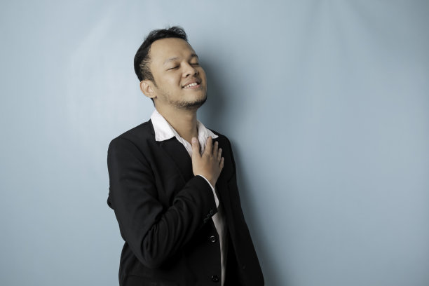 照片中，穿着被蓝色背景隔开的西装的亚洲男性正在微笑图片下载