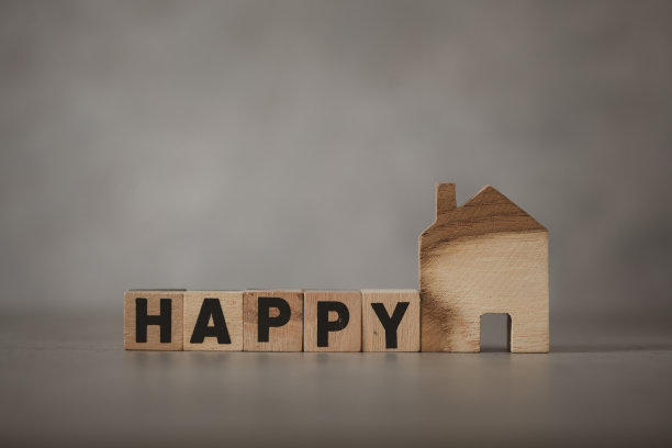 木块上写着“快乐”，就在木房子旁边。幸福家庭的概念图片下载