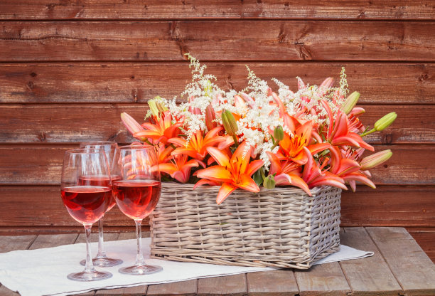 几杯玫瑰酒，柳条篮子里插着橙百合和白色的落新欢花。图片下载