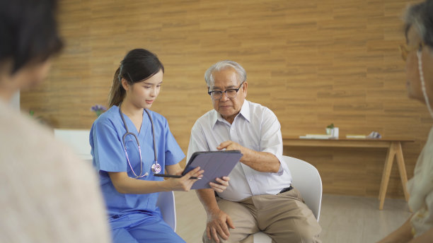 一位亚洲护士与一群老年病人或领取养老金的人交谈，他们微笑着，放松着，一起在养老院玩耍。高级生活方式活动娱乐。退休。卫生保健图片下载