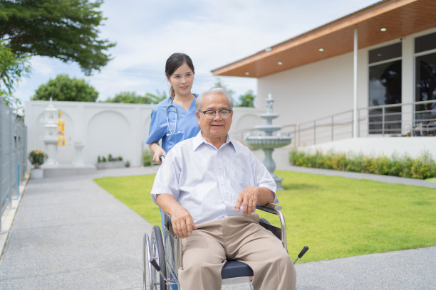 老年残疾亚洲病人或领取退休金者和一名护士使用轮椅到医院的疗养院。老年人生活方式活动娱乐。花园公园保健治疗。图片下载