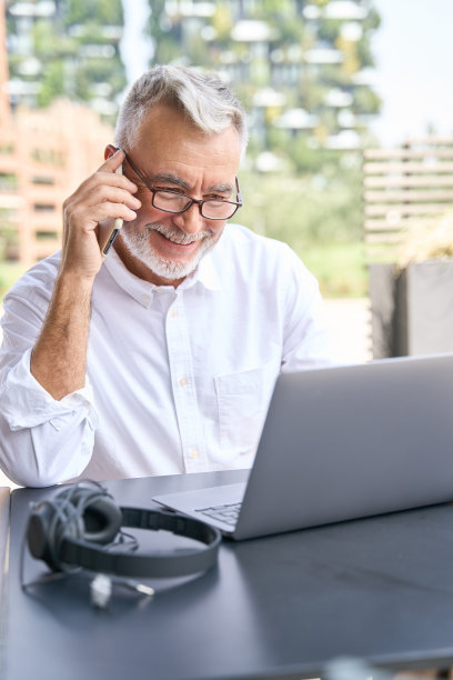 快乐的年长高级商务人士在户外用手机打电话。图片下载