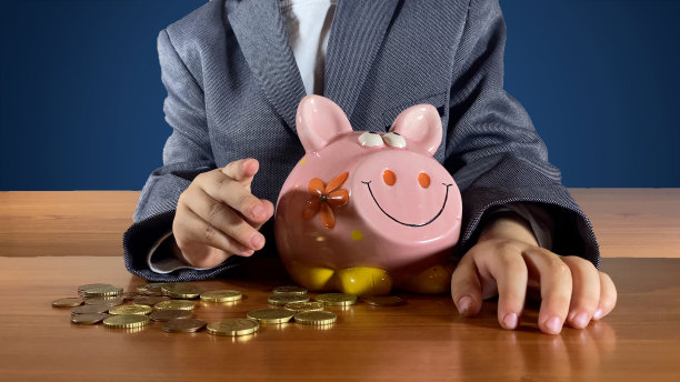 穿西装的孩子在储蓄罐旁边指着手指。理财教育，为孩子储蓄的概念图片下载