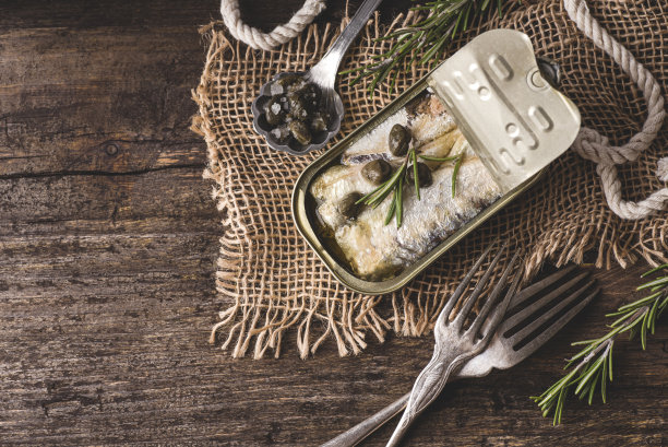 Canned sardines and simple canned fish recipes with capers and rosemary on the rustic wooden table. Easy and healthy lunch. Сanned or tinned fish  is one of the food trends of 2023, top view, copy space图片下载