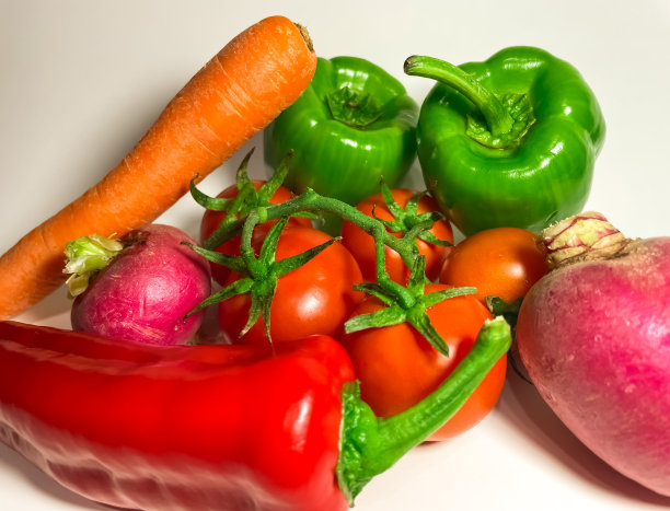 静物的一支成熟的西红柿，绿色和红色的辣椒，胡萝卜，萝卜在一个白色的背景特写图片下载