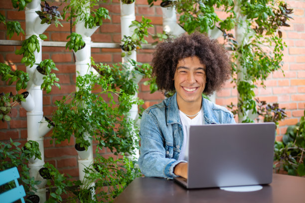 年轻的少数民族男子，穿着便服，在大自然的绿色区域，背景是一个拥有现代水培系统的智能花园。可持续的工作环境绿色空间图片下载
