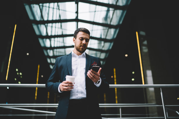 身着正装的商人在办公大楼用智能手机上网图片下载