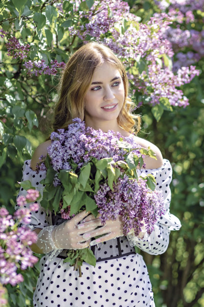 一个微笑的年轻女孩的肖像在盛开的丁香树。夏天的时间,假期图片下载