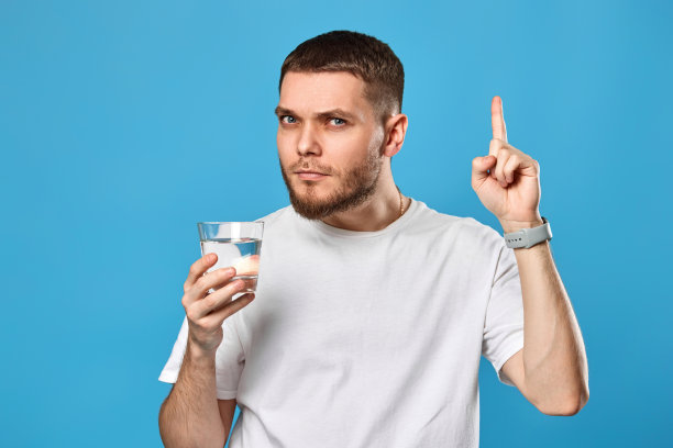 一个穿着白t恤的男人拿着水杯指着上面图片下载