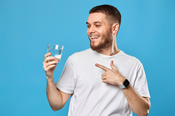 穿着白t恤的快乐帅哥展示着一杯水图片下载