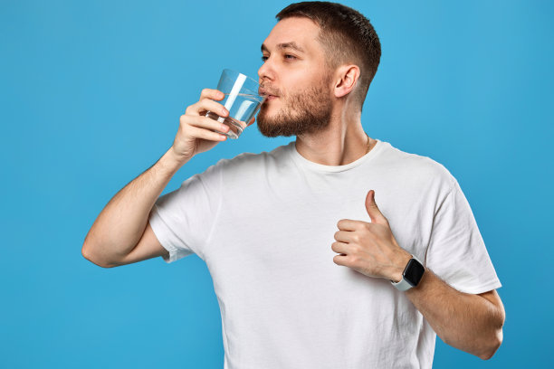 英俊的年轻人用玻璃杯喝水图片下载