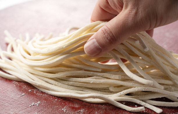 一个男人的手拿着新鲜的乌冬面。图片下载