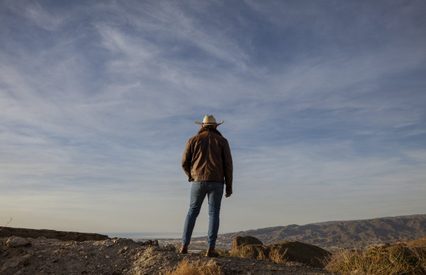 戴着牛仔帽的成年男子站在山顶上。西班牙阿尔梅里亚图片下载