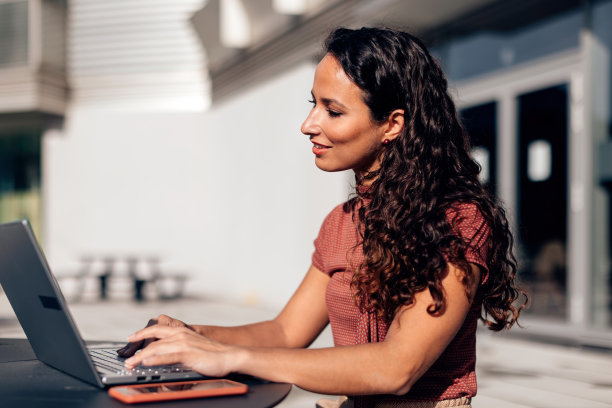 坐在拉丁美洲的女士在阳光明媚的日子里在笔记本电脑上工作图片下载