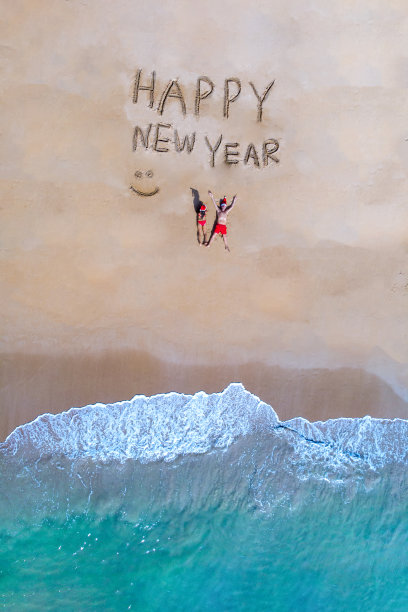 在泰国普吉岛的沙滩上，一对夫妇在沙滩上戴着圣诞帽，新年快乐图片下载