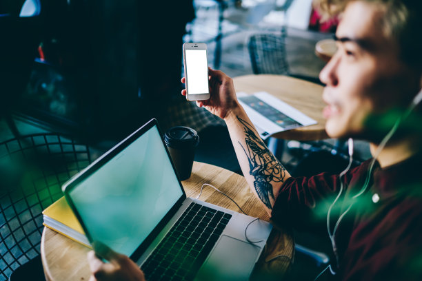 亚洲男性在自助餐厅的笔记本电脑前浏览手机图片下载