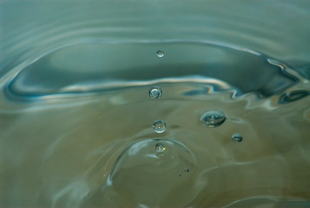 在模糊的背景下，小水滴落入一堆水中的特写镜头图片下载