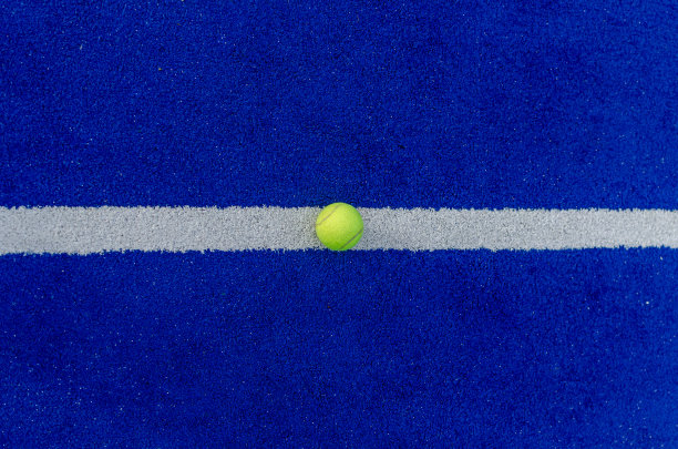一个球在蓝色合成桨网球场的线上的头顶照片。图片下载