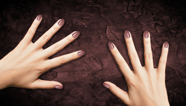 美丽的打扮女人的手春天棕色指甲设计在棕色的背景。美甲、足疗美发沙龙概念。图片下载