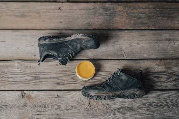 皮革户外鞋或靴子与维护设置在木质背景。图片下载