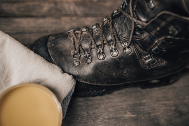 皮革户外鞋或靴子与维护设置在木质背景。图片下载