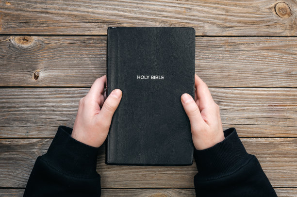 圣经在男性手中的木制背景，俯视图。图片下载