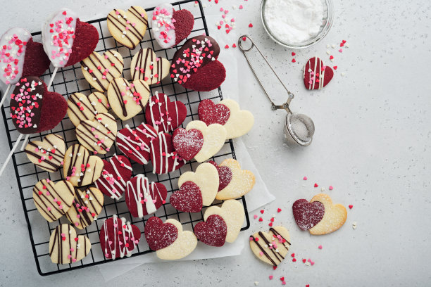 情人节饼干。酥饼内甜红心巧克力釉在粉红盘灰色背景。母亲的一天。女人的一天。甜蜜的节日烘焙。情人节卡片。前视图。图片下载