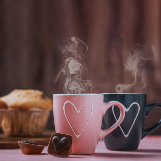 两个粉红色和黑色的心形咖啡杯，松饼和巧克力特写图片下载