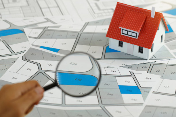 男子拿着放大镜在地籍图上寻找购买土地的估价。房地产概念，空置土地用于建筑建设和住宅细分出售，出租，购买，投资图片下载