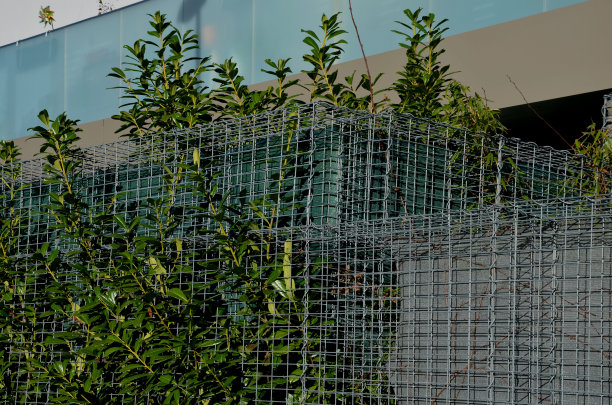 石笼铁丝篮，笼子。花园前的栅栏具有自然的工业外观。由镀锌丝制成。用折叠石头填充的挡土墙。一个隔音屏障保护着居民区和灌木丛图片下载
