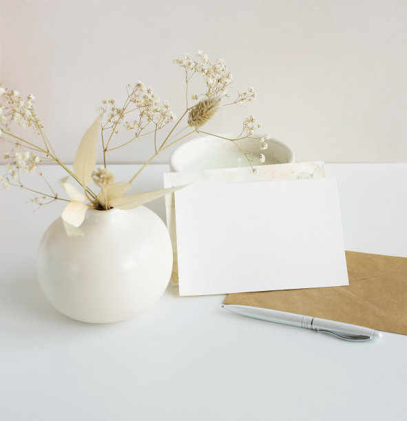 贺卡模型，信封和花瓶在米色的背景干花。卡片模型与复制空间。图片下载