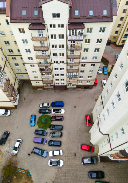 高层公寓楼之间停车场上停放的汽车的鸟瞰图。图片下载