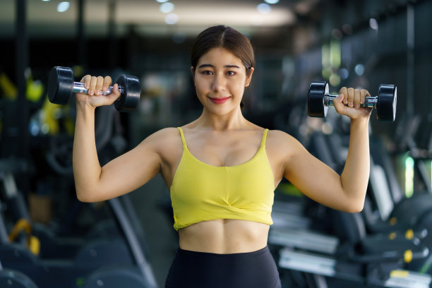 年轻漂亮的亚洲女人在健身房锻炼保持健康。适合女性锻炼哑铃重量。图片下载