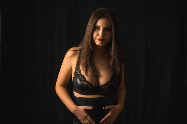 一名身着乳胶内衣的西班牙女性在黑色背景下摆拍图片下载