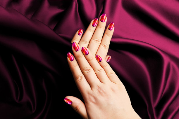 粉色女人的美甲在黑暗的织物背景。图片下载