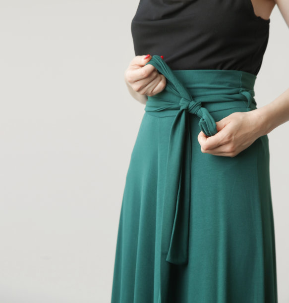 一系列的工作室照片，年轻的女模特在舒适而时尚的棉衣，黑色大便和翠绿色的裙子。图片下载