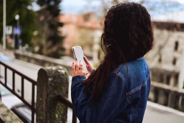 女子与手机背面视图模糊的背景图片下载